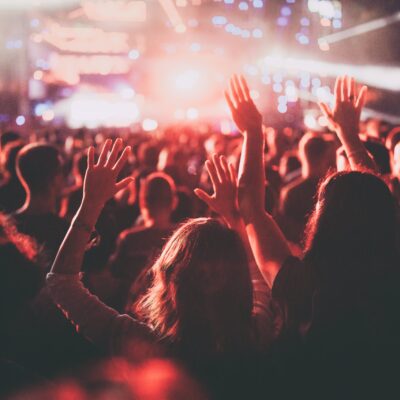 Back view of a crowded audience on a music festival with their arms raised.